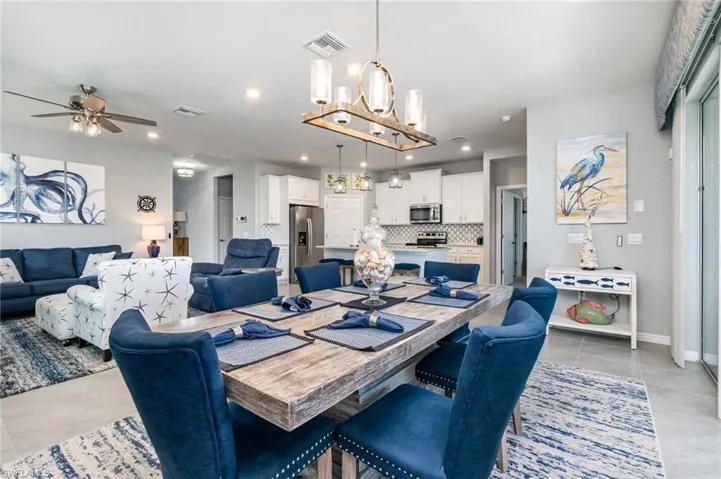 Dining room featuring light tile patterned floors, a chandelier, ceiling fan, and recessed lighting
