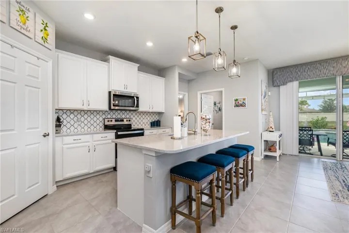 Kitchen with tasteful backsplash, a breakfast bar, a kitchen island with sink, appliances with stainless steel finishes, and light tile patterned floors