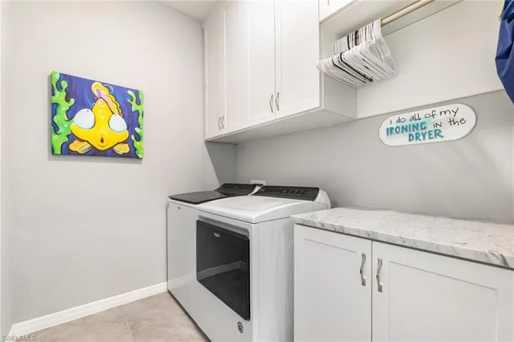 Laundry area featuring cabinet space, separate washer and dryer, and light tile patterned floors