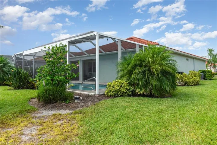 Back of house featuring glass enclosure, a sunroom, a lawn, and stucco siding
