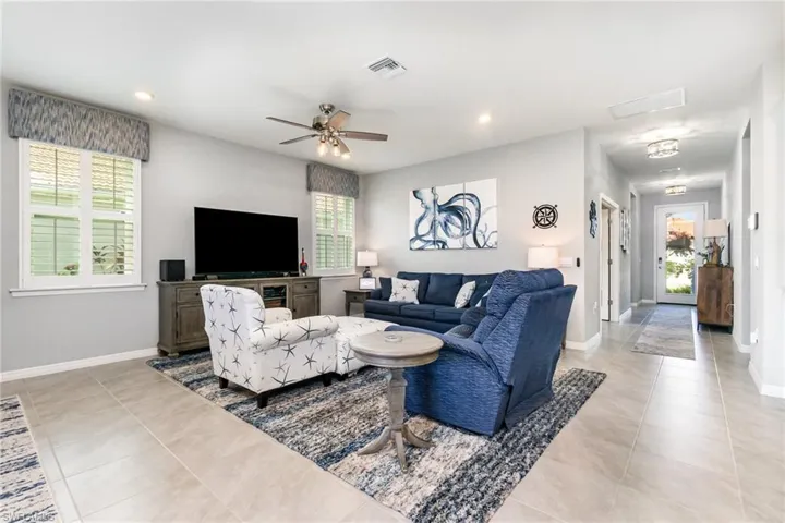 Living area featuring healthy amount of natural light, a ceiling fan, recessed lighting, and light tile patterned floors