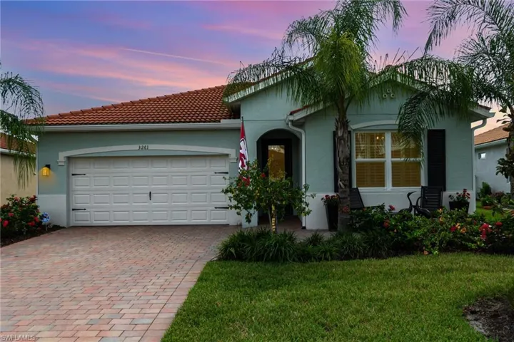 View of front of home with decorative driveway, stucco siding, an attached garage, a tiled roof, and a yard