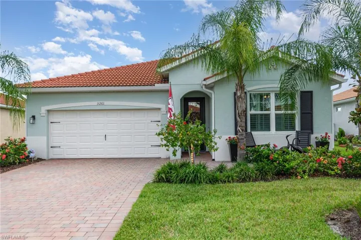 View of front facade with stucco siding, decorative driveway, a front yard, a tiled roof, and a garage