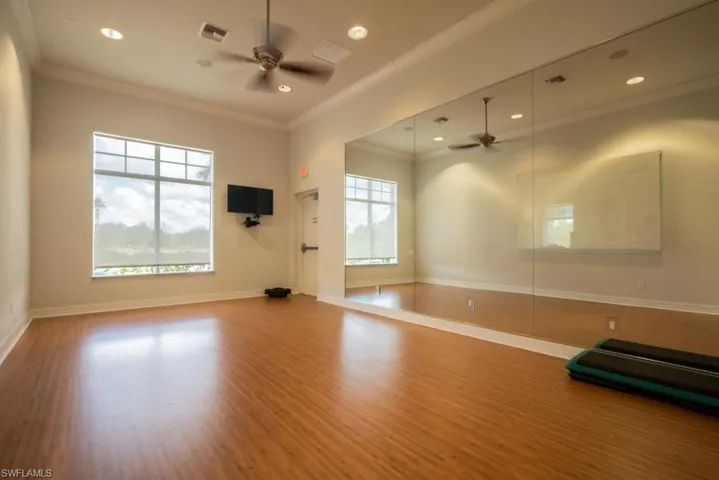 Exercise area featuring healthy amount of natural light, crown molding, a ceiling fan, wood finished floors, and recessed lighting