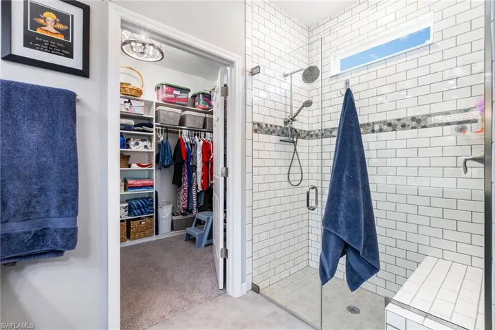 Full bathroom with a stall shower, a spacious closet, and light tile patterned floors