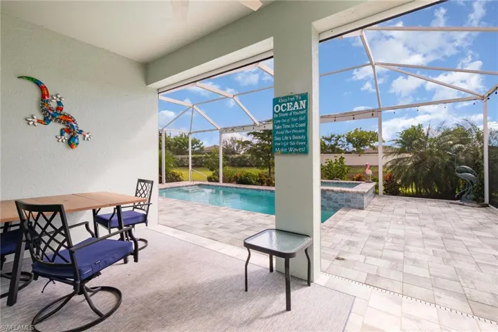 View of swimming pool with a sunroom, a patio area, glass enclosure, a pool with connected hot tub, and outdoor dining area