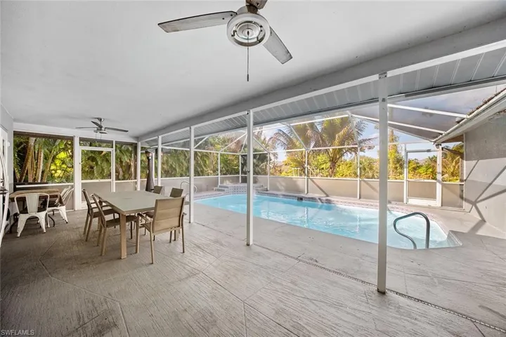 View of pool with outdoor dining area, a sunroom, glass enclosure, and patio surround