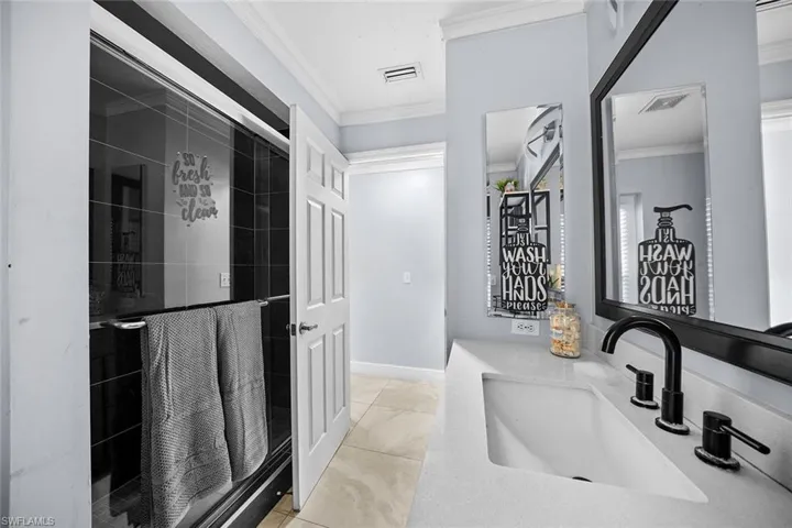 Bathroom featuring a stall shower, vanity, ornamental molding, and light tile patterned floors