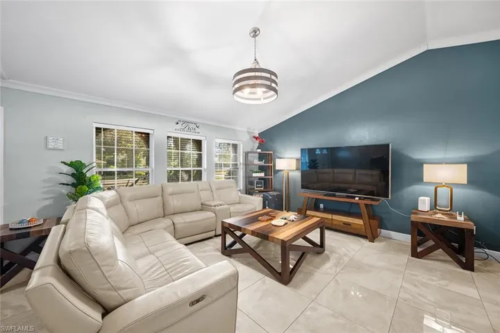 Living area with crown molding, lofted ceiling, and a chandelier