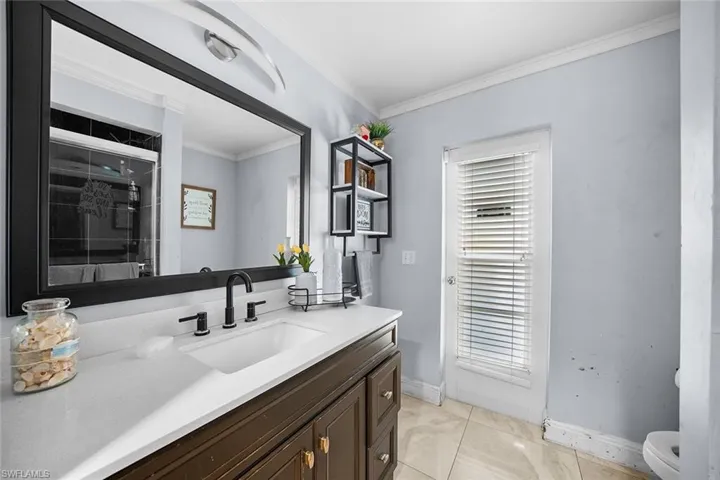Full bathroom with crown molding, vanity, light tile patterned flooring, and a shower with shower door