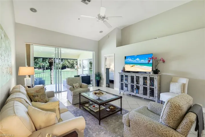 Tiled living room with ceiling fan and vaulted ceiling