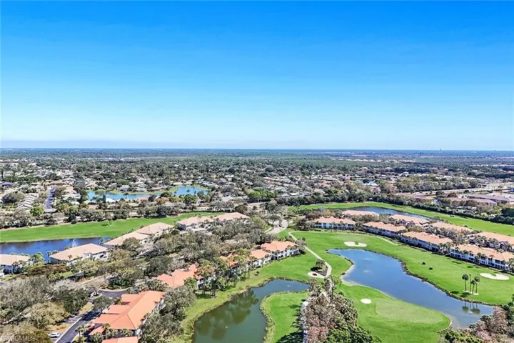 Aerial perspective of suburban area with a nearby body of water and a golf course