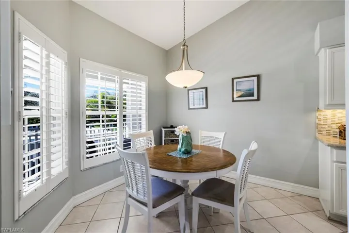 Dining area featuring light tile patterned flooring and vaulted ceiling