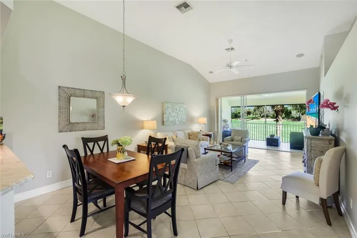 Dining area featuring vaulted ceiling, light tile patterned floors, and a ceiling fan