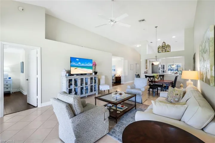 Living area with light tile patterned floors, ceiling fan, and a high ceiling