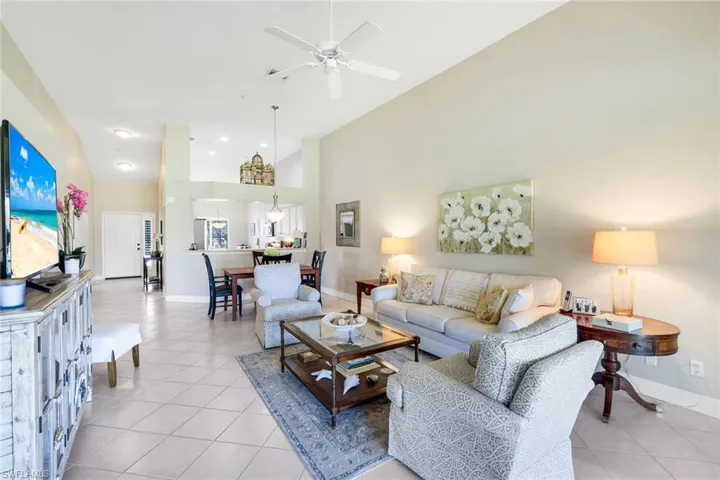 Living room with ceiling fan, light tile patterned floors, and a high ceiling