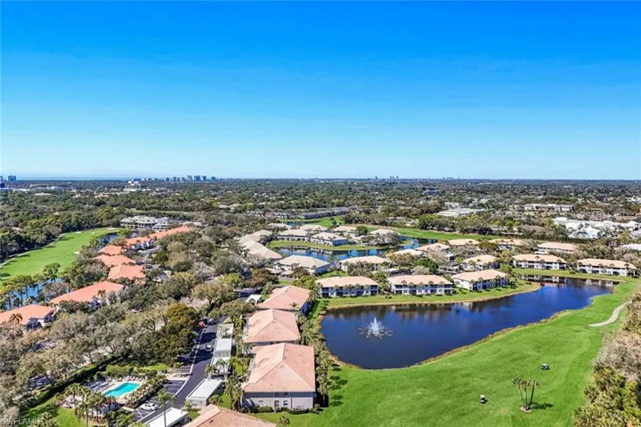 Aerial perspective of suburban area featuring a local golf course and a nearby body of water