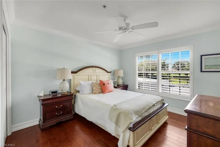 Bedroom featuring dark wood-style floors, ornamental molding, and a ceiling fan