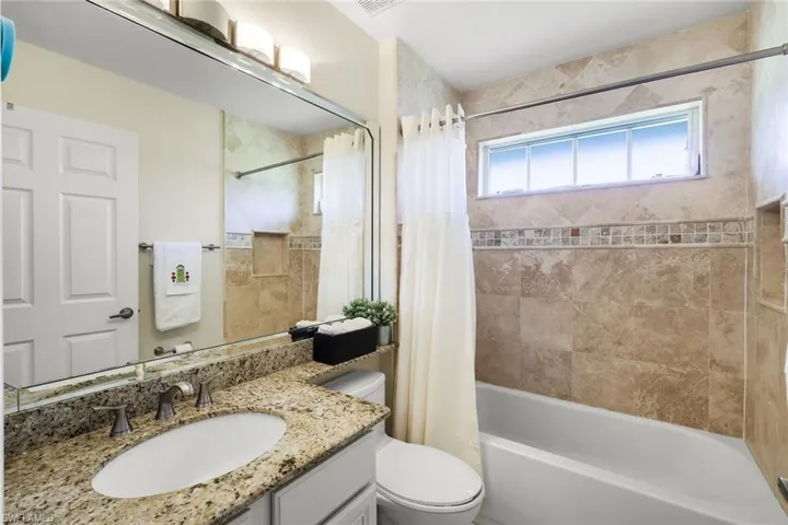 Bathroom featuring vanity and shower / bathtub combination with curtain