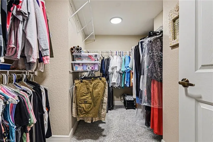 Walk in closet featuring light colored carpet