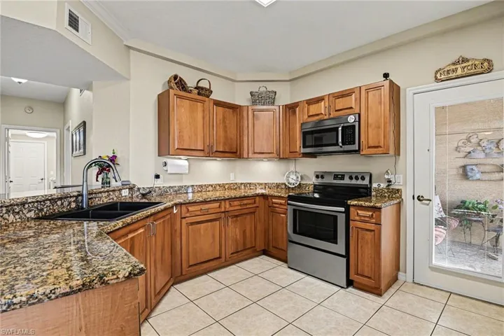 Kitchen with dark stone countertops, wood finish cabinetry, stainless steel appliances, and a peninsula