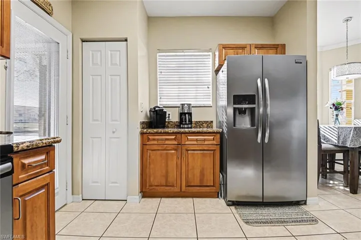Kitchen with stainless steel fridge with ice dispenser, dark stone countertops, plenty of natural light, and wood finish cabinets