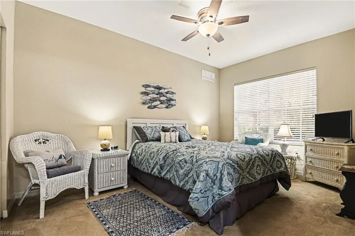 Carpeted bedroom with ceiling fan and baseboards