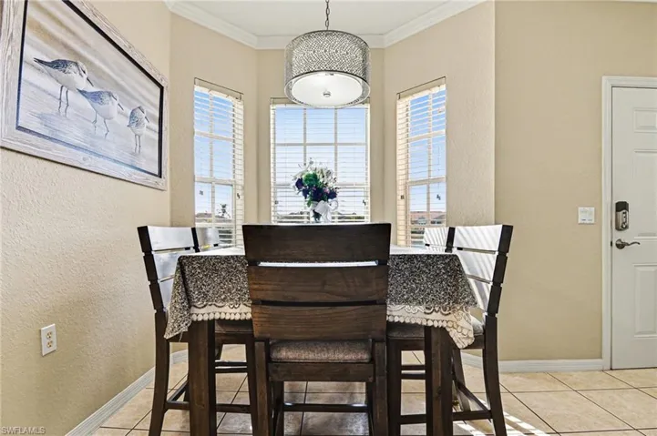 Dining area featuring crown molding, light tile patterned floors, and a textured wall