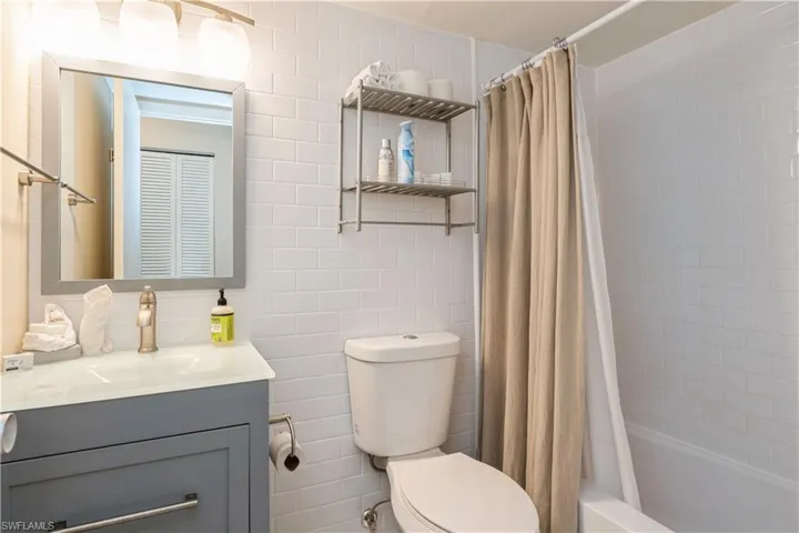 Full bathroom featuring vanity, toilet, tile walls, and shower / bathtub combination with curtain