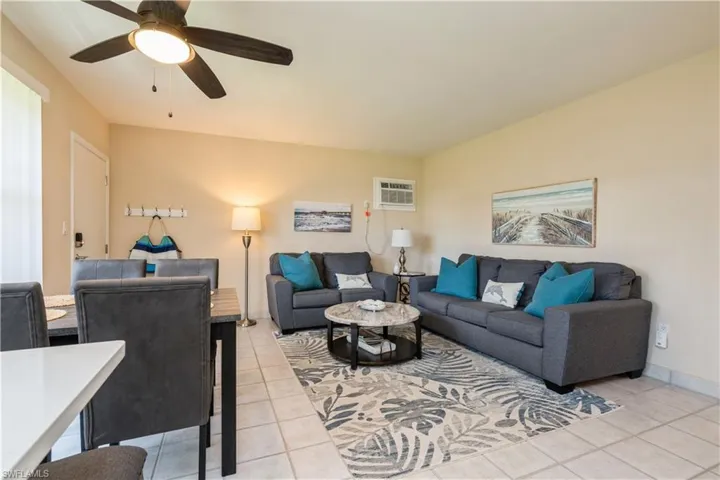 Tiled living room featuring ceiling fan and a wall mounted air conditioner