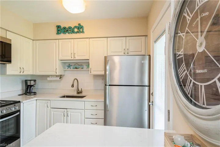 Kitchen with white cabinets, appliances with stainless steel finishes, tasteful backsplash, and sink