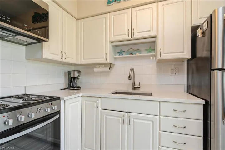 Kitchen with white cabinets, stainless steel appliances, decorative backsplash, and sink