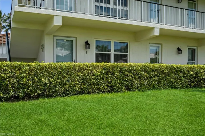 View of exterior entry featuring a balcony and a yard
