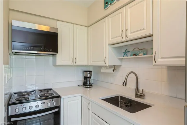 Kitchen with white cabinetry, appliances with stainless steel finishes, tasteful backsplash, and sink