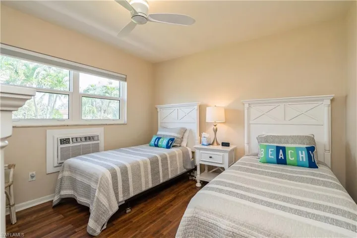 Bedroom featuring ceiling fan, dark hardwood / wood-style flooring, and an AC wall unit