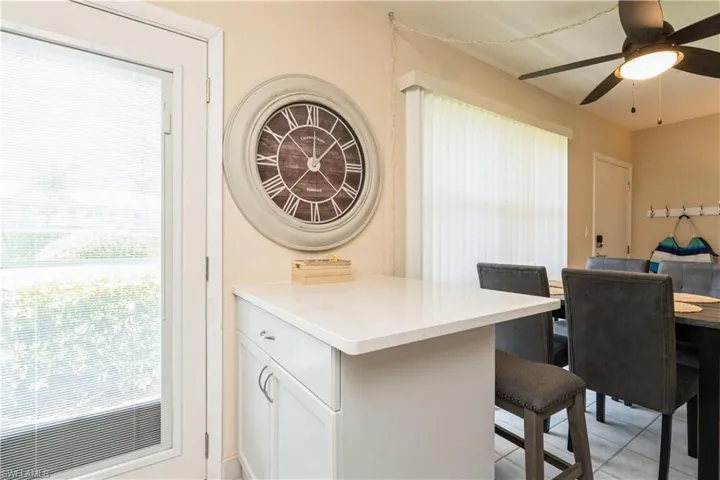 Kitchen featuring white cabinets, light tile patterned floors, ceiling fan, and a breakfast bar