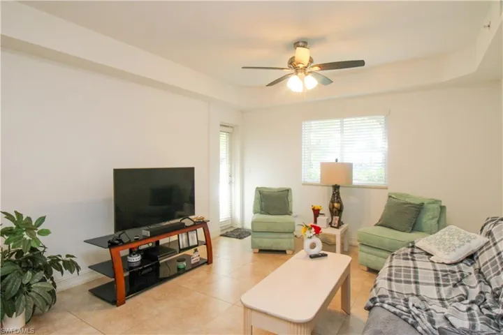 Living room with ceiling fan and light tile patterned flooring