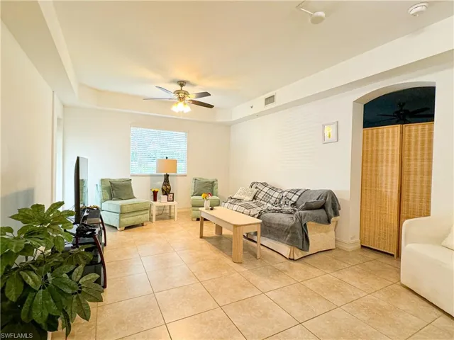Tiled living room featuring a tray ceiling and ceiling fan