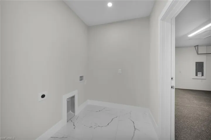 Dedicated laundry area featuring a white marble-look tile floor, recessed ceiling lighting, and crisp white baseboards