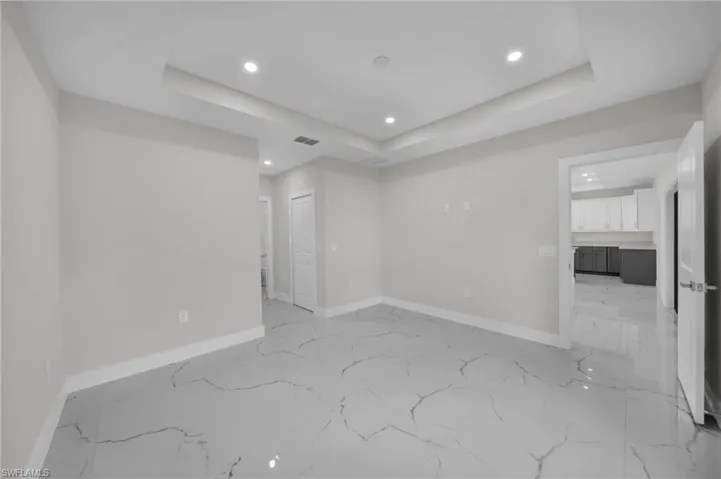 Spacious interior featuring large format tile flooring, recessed lighting, and a tray ceiling