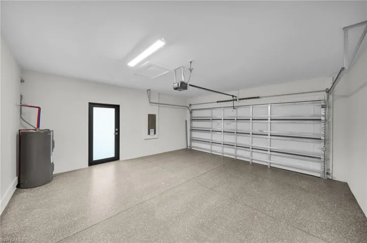 Spacious garage featuring a finished epoxy floor, an overhead lighting fixture, and a black framed door with frosted glass
