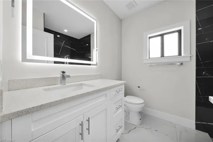 Bathroom featuring a white vanity with integrated sink, a quartz-finish countertop, and brushed nickel hardware