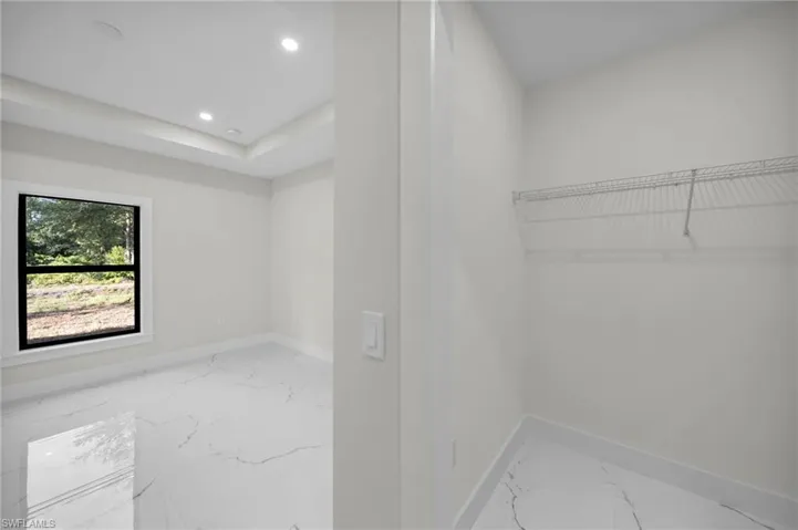 Room featuring a tray ceiling with recessed lighting, a window with black trim, and white-finish flooring