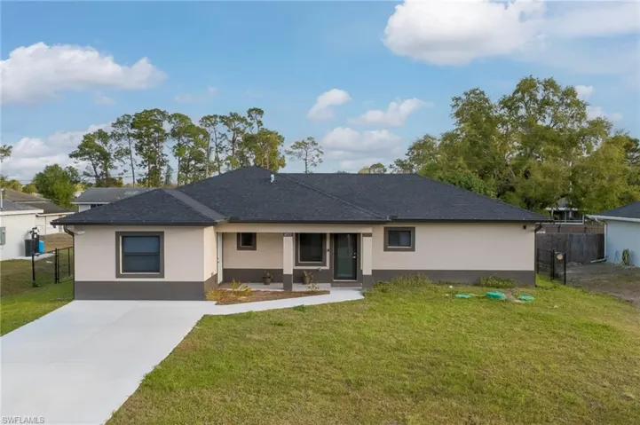 View of front facade with stucco siding, driveway, and a shingled roof