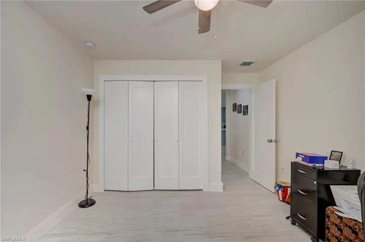 Bedroom featuring light marble finish floors, a closet, and ceiling fan