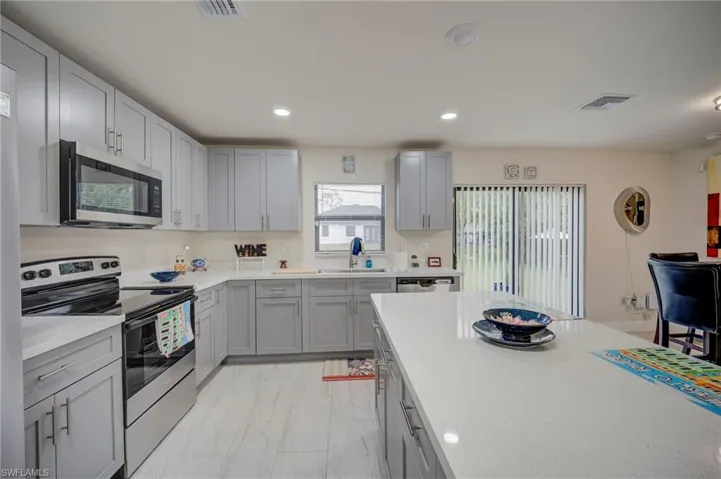 Kitchen featuring stainless steel appliances, gray cabinetry, recessed lighting, and light stone counters