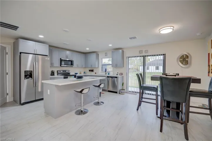 Kitchen featuring stainless steel appliances, a kitchen breakfast bar, gray cabinets, a kitchen island, and light countertops