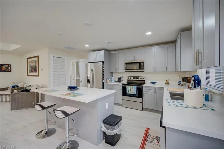 Kitchen featuring stainless steel appliances, a center island, open floor plan, a kitchen bar, and recessed lighting
