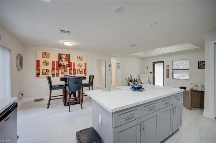 Kitchen with gray cabinetry, dishwasher, and a kitchen island