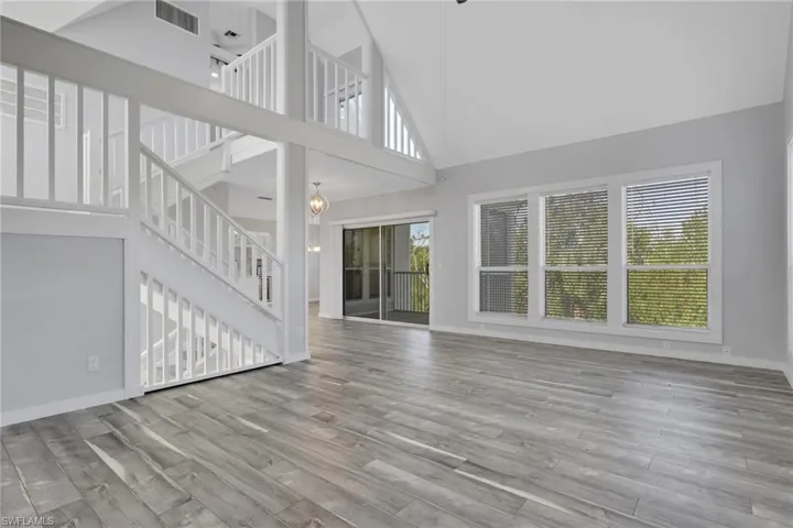 Unfurnished living room featuring plenty of natural light, a high ceiling, light wood-type flooring, and a ceiling fan